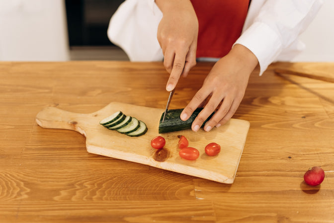 person slicing cucumber