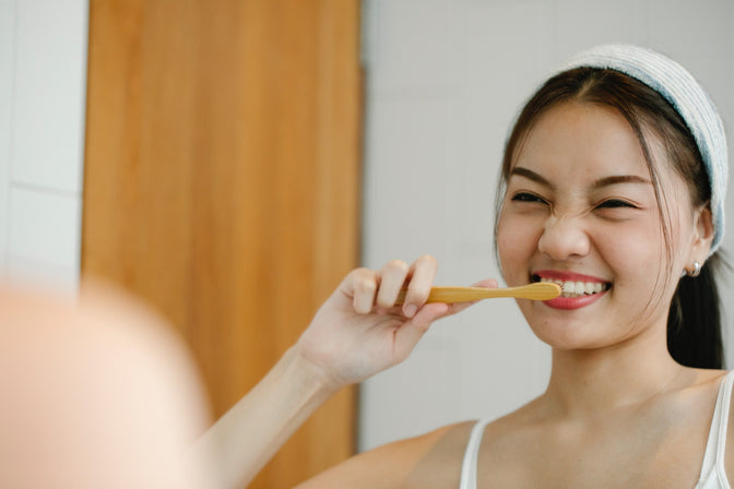 woman brushing teeth to improve oral health