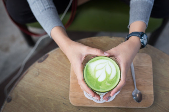 person holding cup of matcha tea