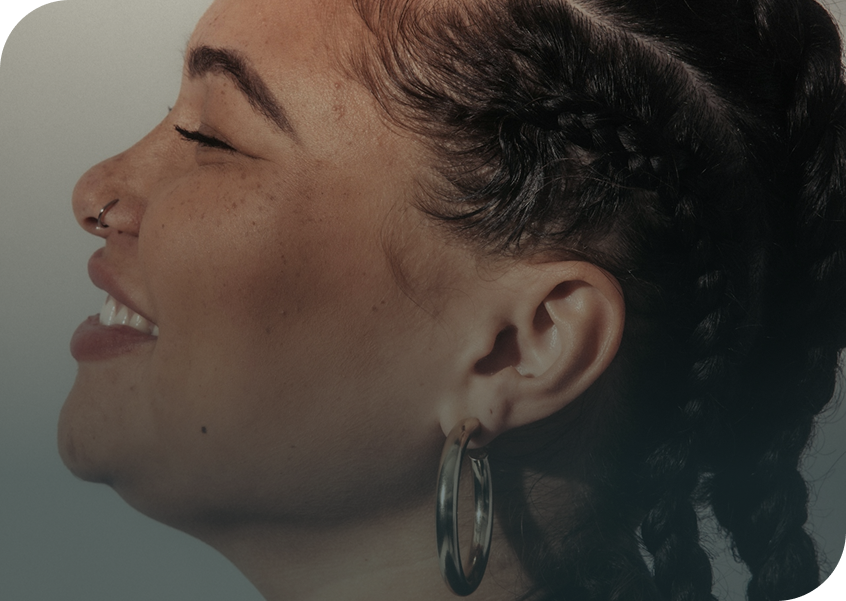 Close-up of a person with braided hair wearing a hoop earring on a neutral background
