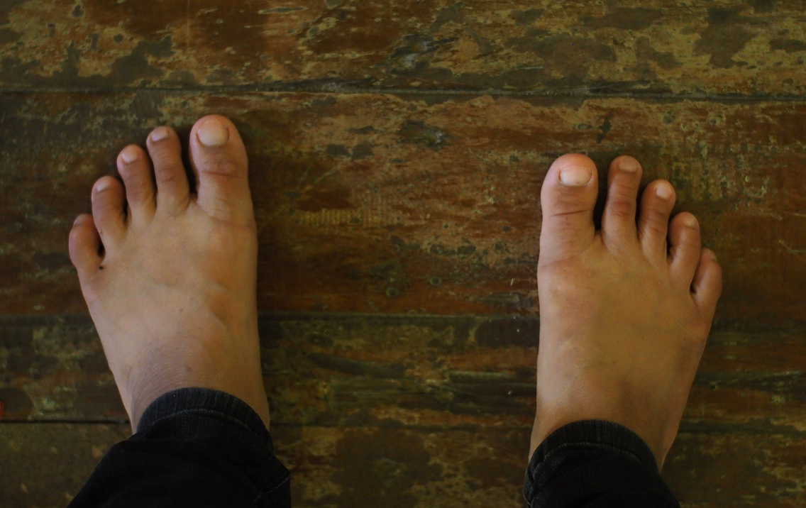 Two feet standing on a wooden floor